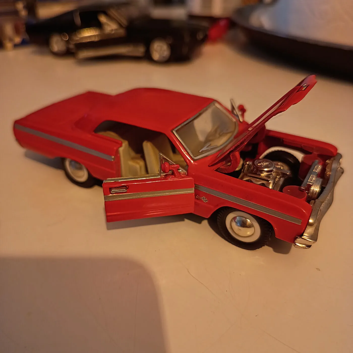 Rød skala modelbil med åben motorhjelm og dør